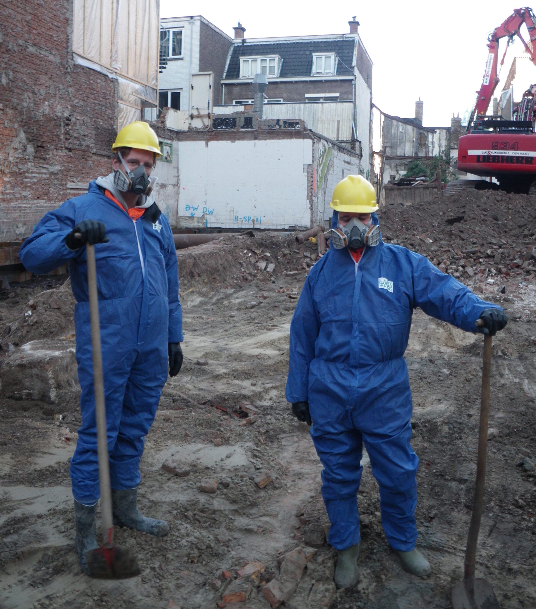Opgraven in vervuilde grond; gewapend met helm, beschermende overall en stofmasker (2012)